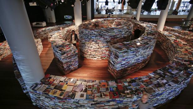 Eine Installation aus gestapelten Büchern formt einen spiralförmigen Gang.