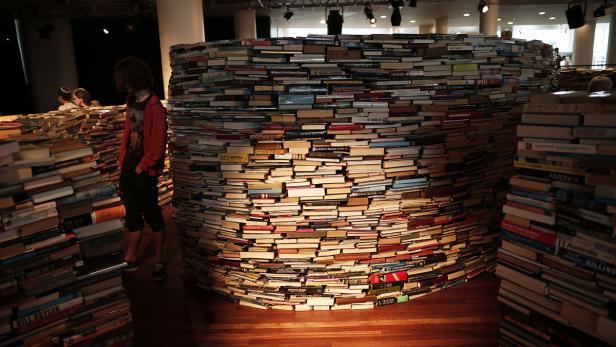 Ein Mann steht vor einer großen, kreisförmigen Installation aus Büchern.