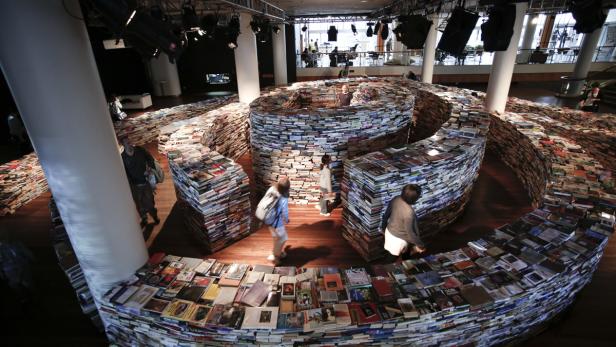 Menschen gehen durch ein Labyrinth, das aus Büchern gebaut wurde.