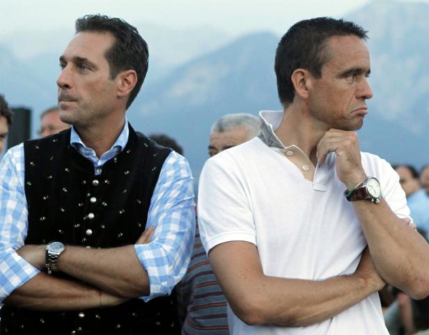 Zwei Männer stehen mit verschränkten Armen vor einer Bergkulisse.