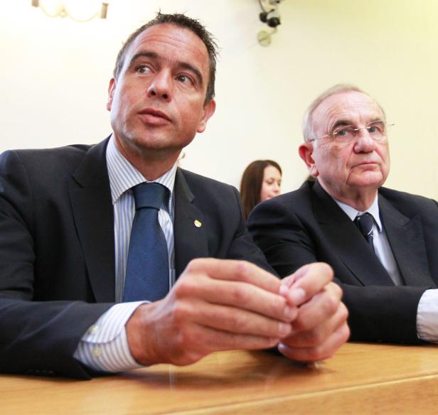 Zwei Männer in Anzügen sitzen an einem Tisch.