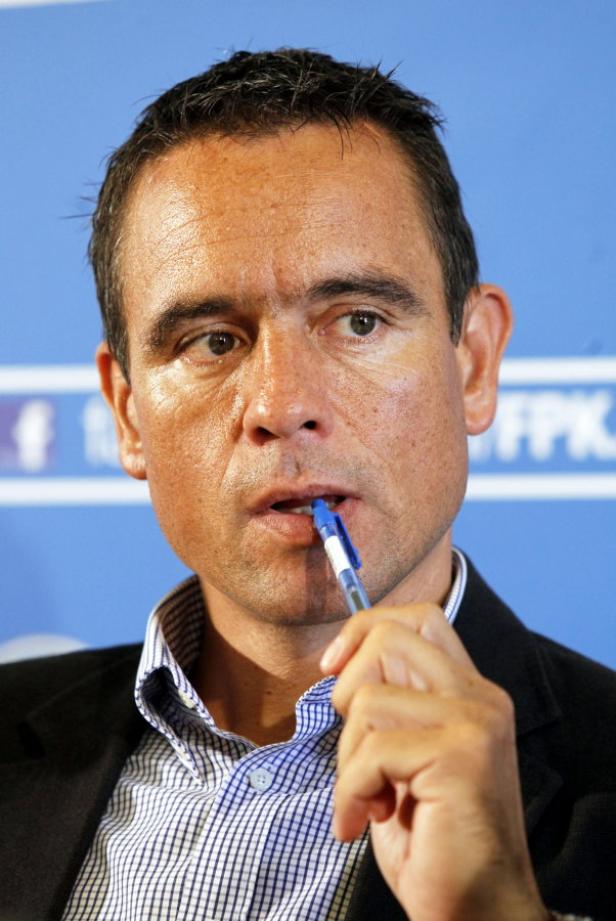 Ein Mann im Anzug hält einen Stift im Mund.