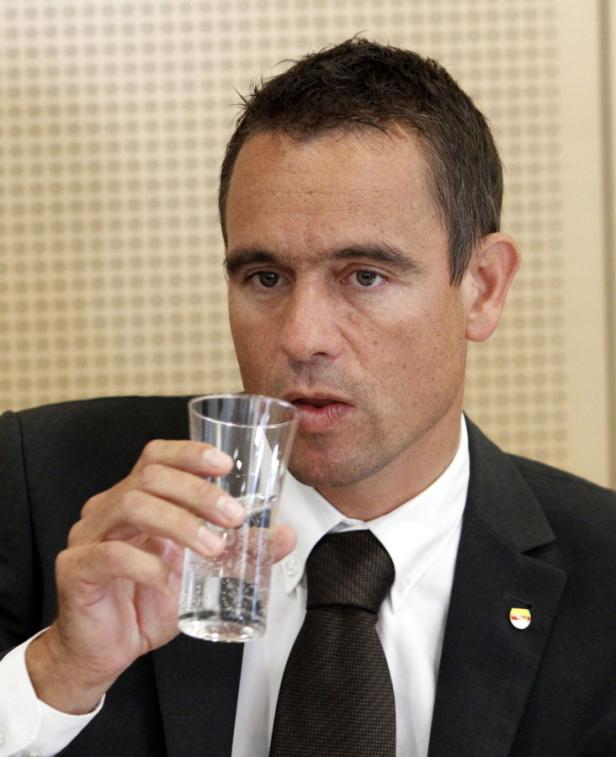 Ein Mann im Anzug trinkt ein Glas Wasser.