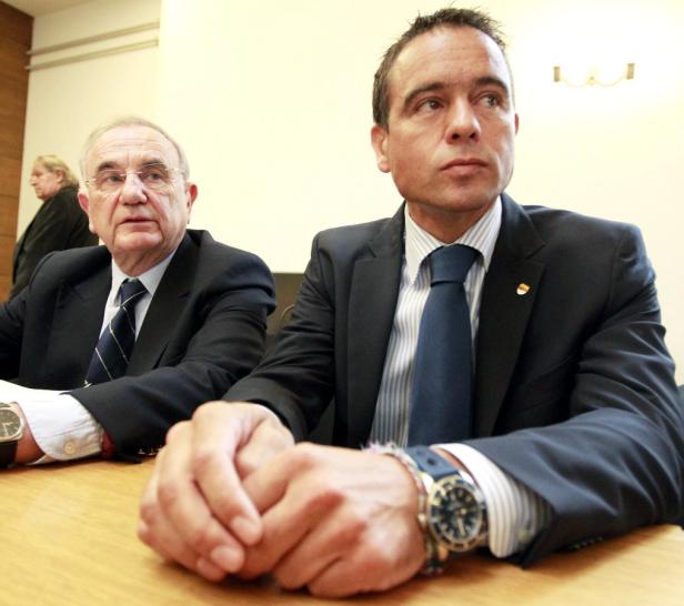 Zwei Männer in Anzügen sitzen an einem Tisch.