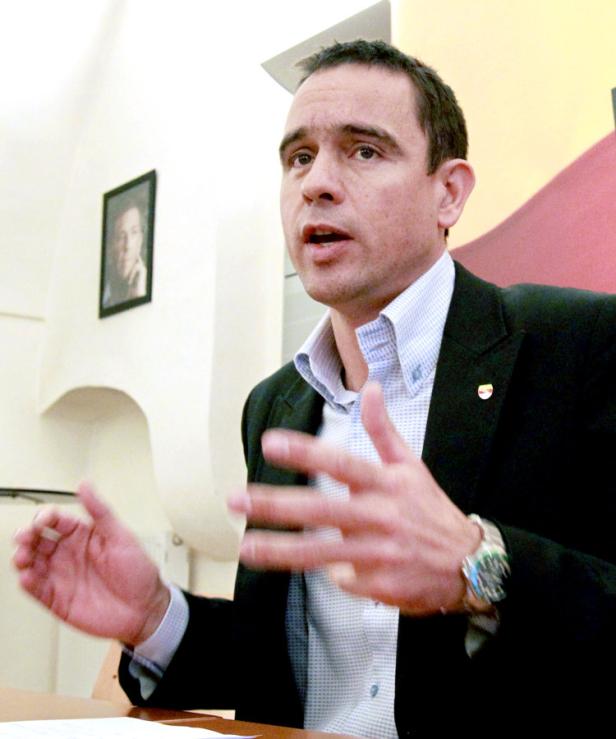 Ein Mann in Anzug gestikuliert während einer Präsentation.