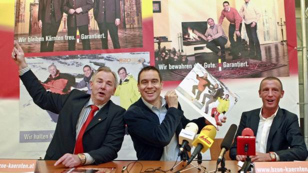 Drei Männer sitzen an einem Tisch mit Mikrofonen vor Wahlplakaten der Partei BZÖ.