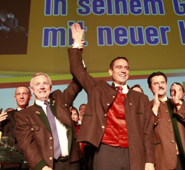 Zwei Männer in Trachtenanzügen stehen auf einer Bühne und heben die Arme.