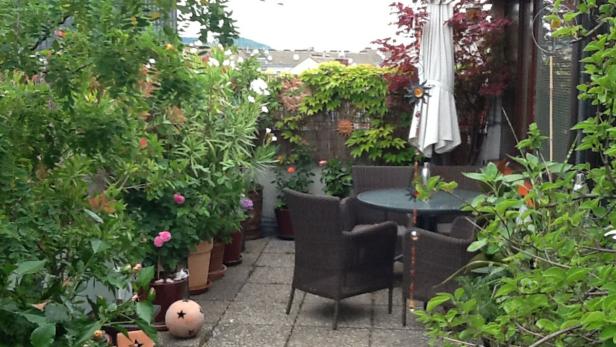 Ein üppiger, begrünter Balkon mit Tisch und Stühlen lädt zum Verweilen ein.