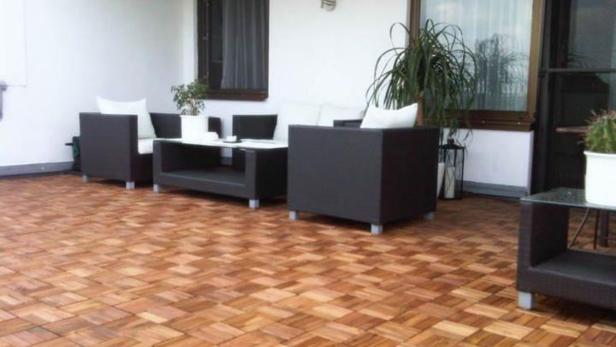 Eine Terrasse mit dunklen Loungemöbeln und einem Holzboden.