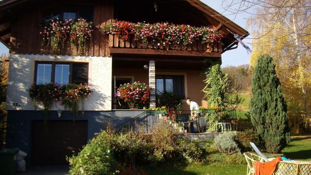 Ein mit Blumen geschmücktes Haus mit einer Person auf der Veranda.