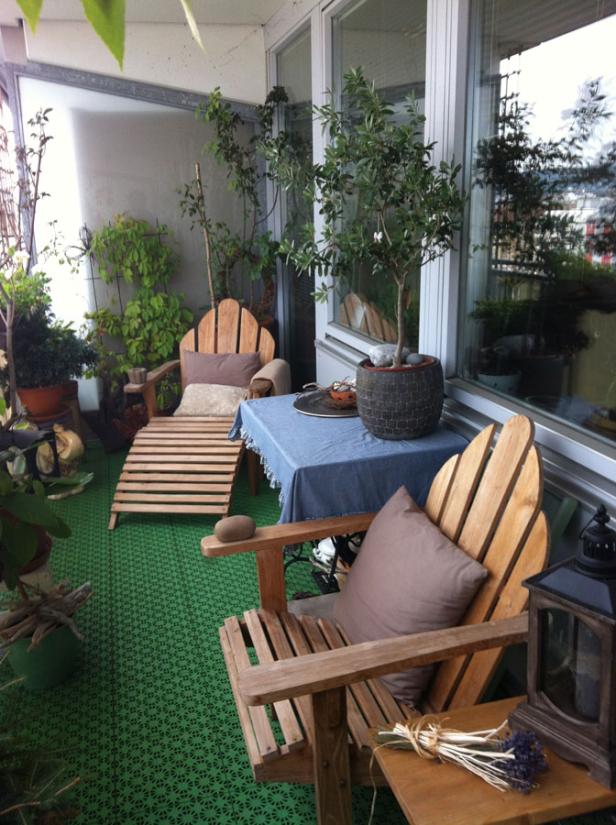 Ein gemütlicher Balkon mit Holzmöbeln und vielen Pflanzen.