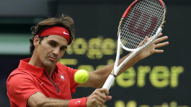 Roger Federer bei einem Tennisspiel im roten Shirt und Stirnband.