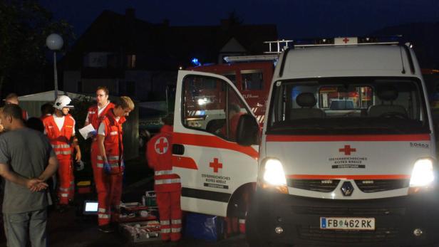 Einsatzkräfte des Österreichischen Roten Kreuzes stehen vor einem Rettungswagen.
