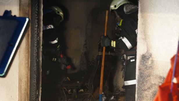 Feuerwehrleute inspizieren einen verrauchten Raum nach einem Brand.