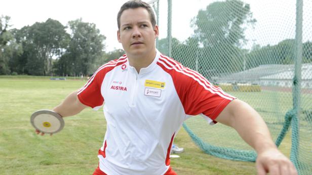 Ein Diskuswerfer in österreichischer Sportbekleidung bereitet sich auf den Wurf vor.