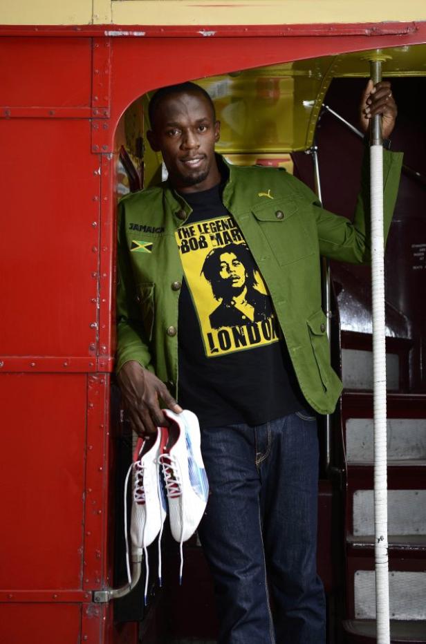 Usain Bolt mit einem Bob-Marley-T-Shirt und Laufschuhen in der Hand.