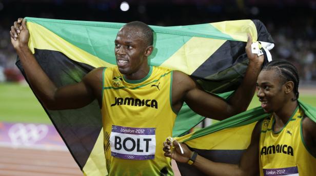 Usain Bolt und ein weiterer jamaikanischer Athlet feiern mit der jamaikanischen Flagge einen Sieg.