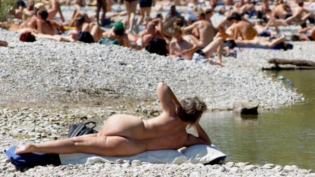 Eine Frau liegt am Ufer eines Flusses, während sich andere sonnen.