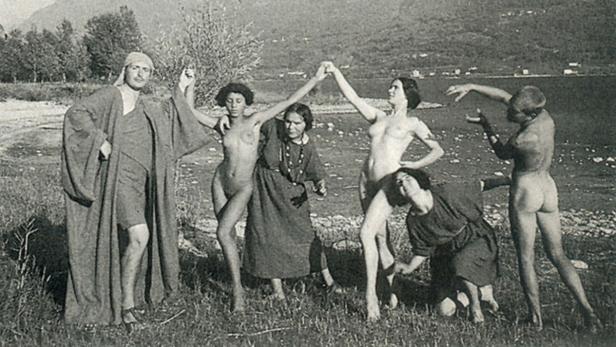 Eine Gruppe von Menschen posiert in einer dramatischen Szene am Ufer eines Sees.