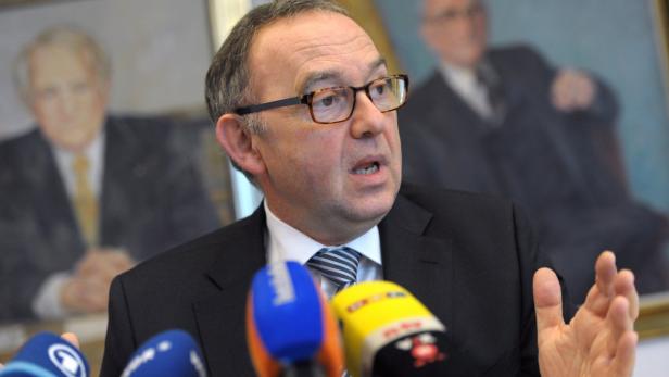 Ist gegen ein Abkommen: NRW-Finanzminister Walter-Borjans Ein Mann mit Brille gestikuliert vor Mikrofonen; im Hintergrund Gemälde.