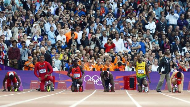 Leichtathleten, darunter Usain Bolt, bereiten sich auf den Start eines Rennens vor einer Zuschauermenge vor.