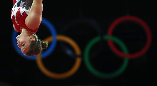 Eine Turnerin bei einer Übung vor dem Hintergrund der Olympischen Ringe.