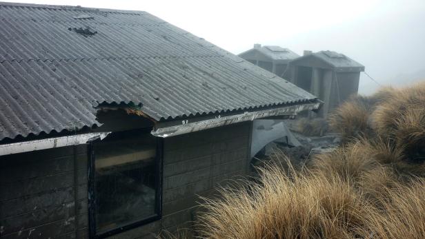 Eine verfallene Hütte mit beschädigtem Dach im Nebel.