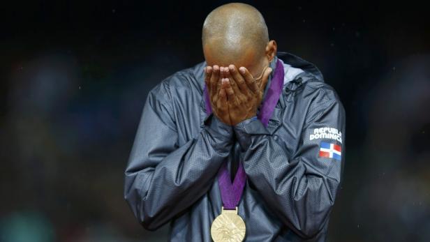 Ein Sportler aus der Dominikanischen Republik mit einer Goldmedaille verdeckt sein Gesicht mit den Händen.