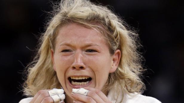 Eine blonde Frau mit bandagierten Fingern weint und lacht gleichzeitig.