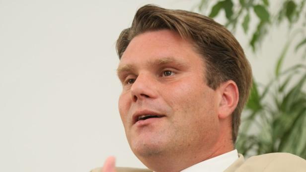 Ein Mann mit blonden Haaren und hellem Teint schaut zur Seite.