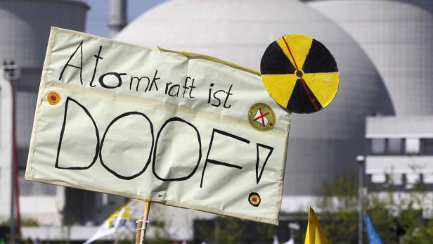 Ein Protestschild mit der Aufschrift „Atomkraft ist DOOF!“ vor einem Atomkraftwerk.