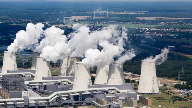 Ein Kohlekraftwerk mit mehreren Kühltürmen stößt Rauch aus.