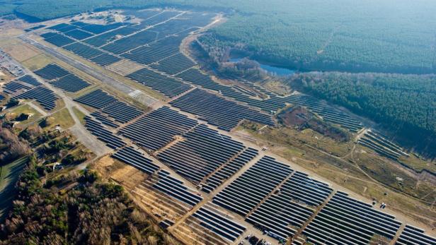 Luftaufnahme eines großen Solarparks neben einem Waldgebiet.