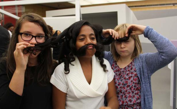 Drei Mädchen posieren mit ihren Haaren als falsche Bärte und Ponyfrisuren.