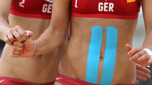 Zwei Beachvolleyballspielerinnen des deutschen Teams mit blauem Tape auf dem Bauch.