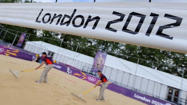 Zwei Männer harken den Sand auf einem Beachvolleyballfeld bei den Olympischen Spielen 2012 in London.