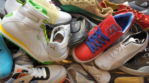 Eine Vielzahl von Puma-Schuhen unterschiedlicher Modelle und Farben liegen übereinander.