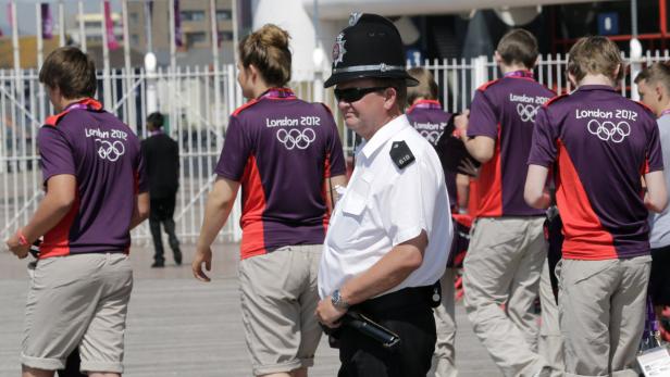 Ein Polizist steht neben einer Gruppe von Freiwilligen bei den Olympischen Spielen 2012 in London.