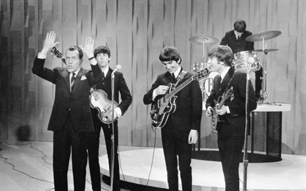 Die Beatles treten mit einem Moderator in einer Fernsehshow auf.