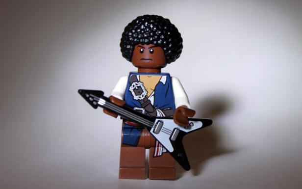 Eine Lego-Figur mit Afro-Frisur hält eine E-Gitarre.