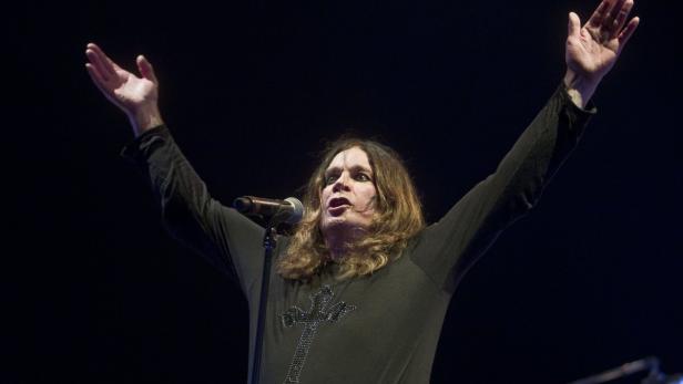 Ozzy Osbourne steht mit erhobenen Armen auf der Bühne.