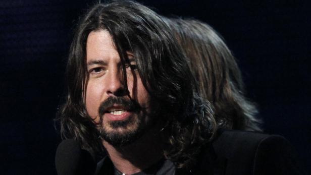 Dave Grohl spricht bei einer Veranstaltung in ein Mikrofon.
