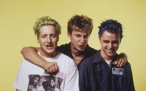 Die kanadische Rockband Sloan posiert vor einem gelben Hintergrund.