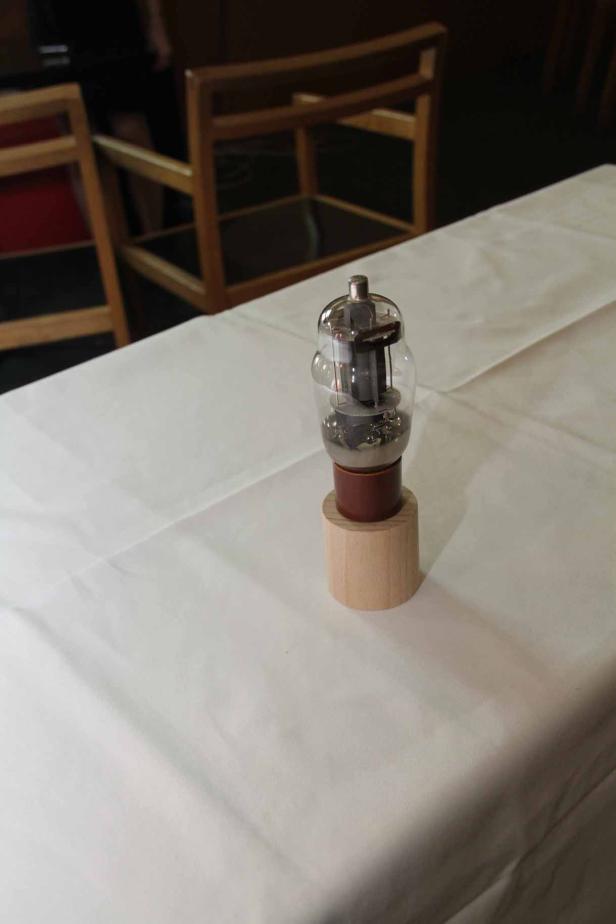 Eine Elektronenröhre steht auf einem Holztisch.
