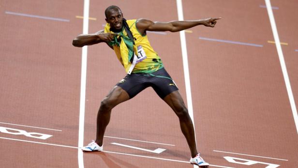 Usain Bolt feiert auf der Laufbahn mit der jamaikanischen Flagge um den Hals.