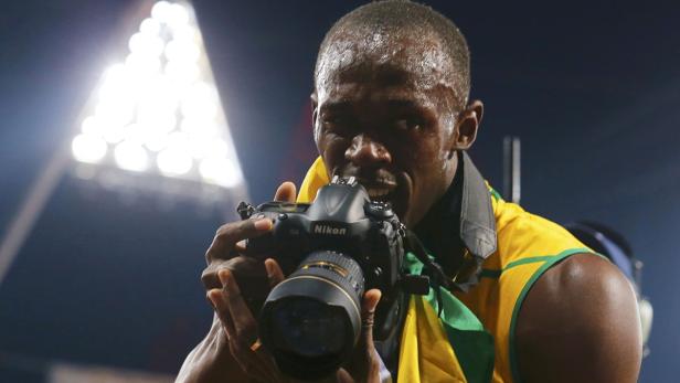 Usain Bolt hält eine Nikon-Kamera vor sein Gesicht und scheint hineinzubeißen.
