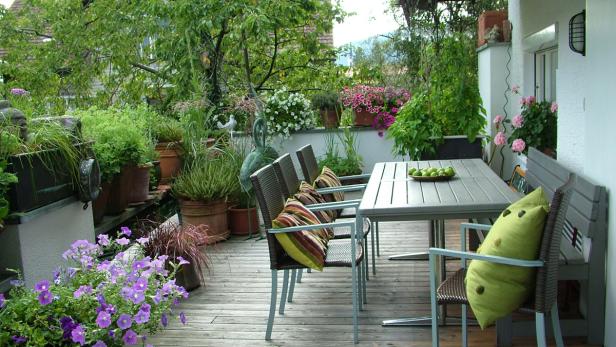 Ein üppiger, begrünter Balkon mit Tisch und Stühlen lädt zum Verweilen ein.