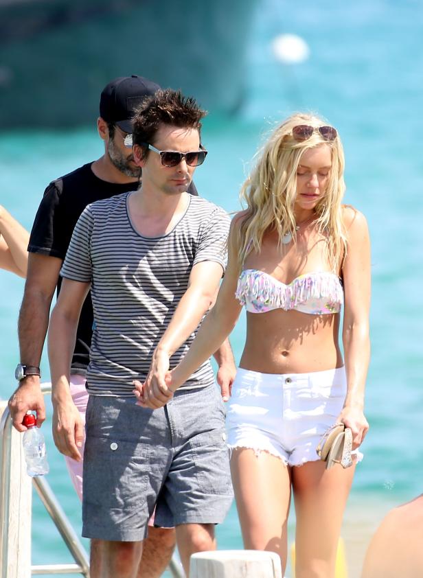 Matt Bellamy und eine Frau halten Händchen am Strand.