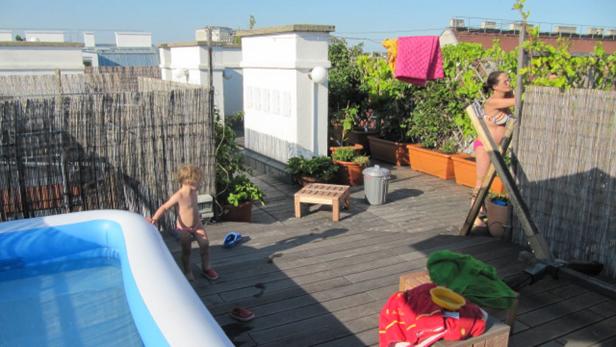 Auf einer Dachterrasse stehen ein Planschbecken, eine Frau und ein Kind.