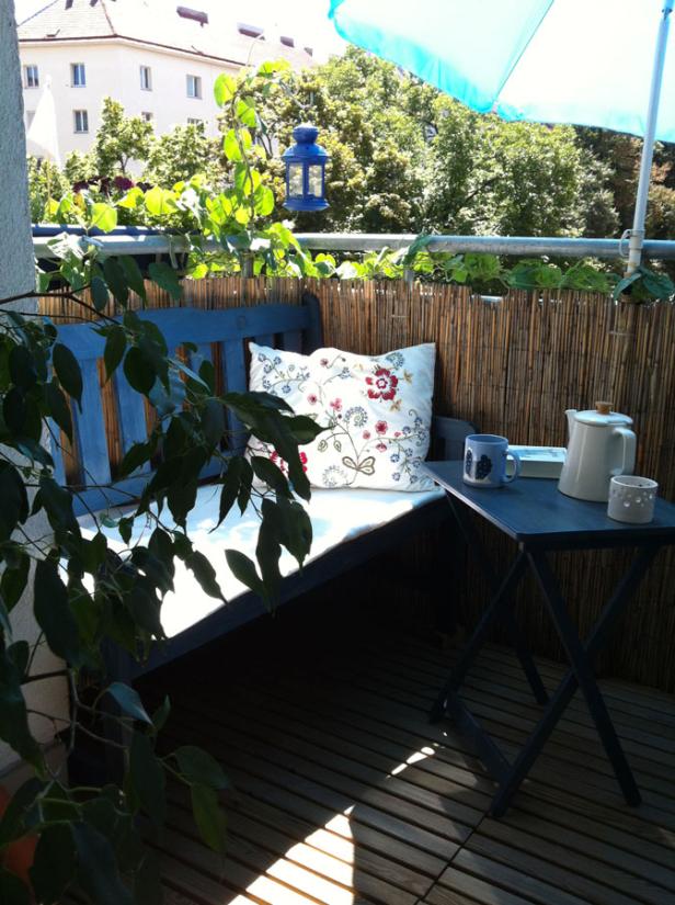 Ein gemütlicher Balkon mit einer Bank, einem Tisch und einer Teekanne.